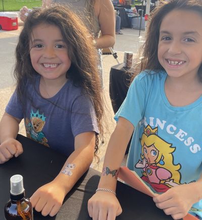 Two girls showing off their temporary tattoos at a Duran Fun Lab event